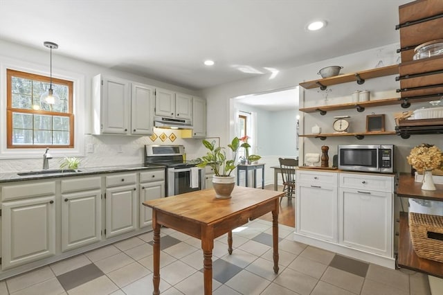 kitchen with pendant lighting, appliances with stainless steel finishes, white cabinets, a sink, and under cabinet range hood