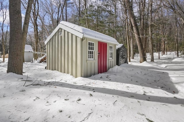 snow covered structure featuring an outbuilding and a storage unit