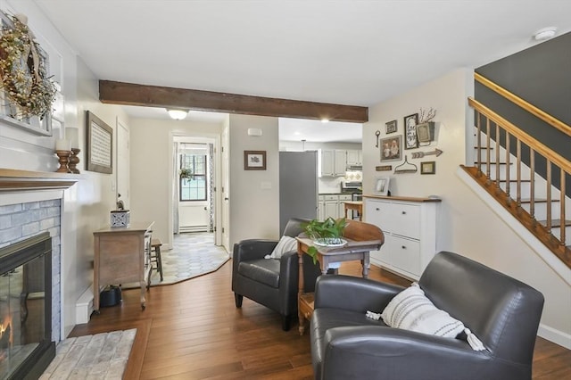 living room with baseboards, stairway, dark wood-style flooring, a fireplace, and beam ceiling