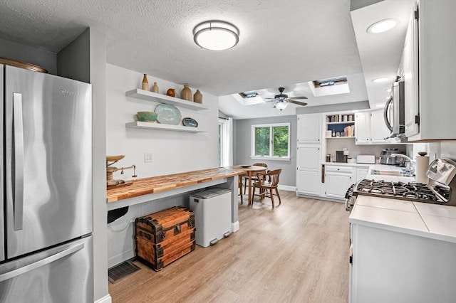 17 High St, Merrimac, MA 01860 - kitchen with freestanding refrigerator, open shelves, a skylight, light wood-type flooring, and a ceiling fan