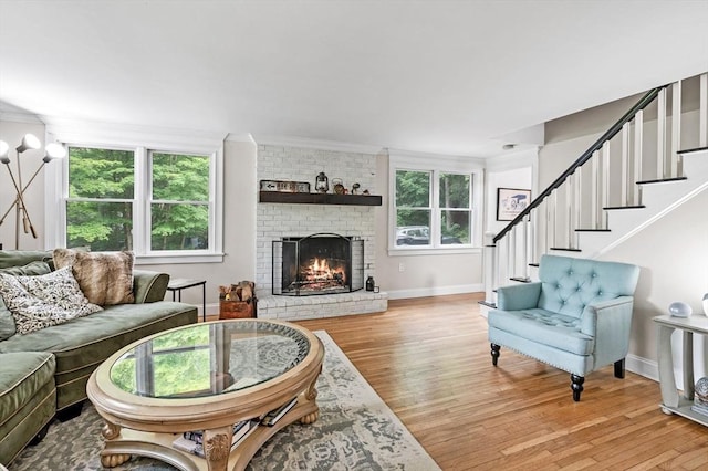 17 High St, Merrimac, MA 01860 - living room with light wood-style flooring, ornamental molding, baseboards, a brick fireplace, and stairs