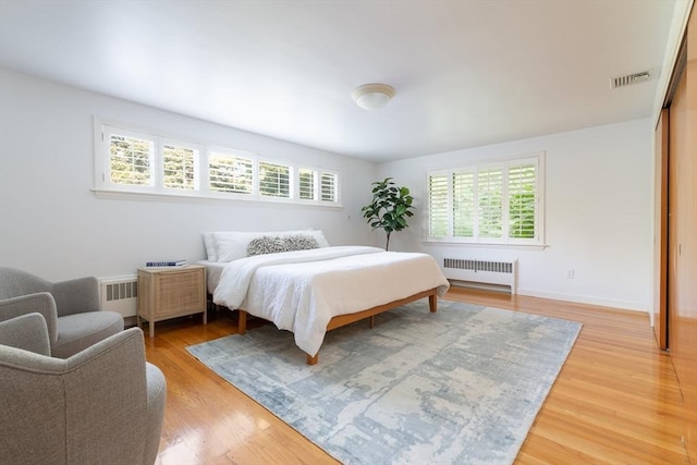 bedroom with radiator heating unit and hardwood / wood-style floors