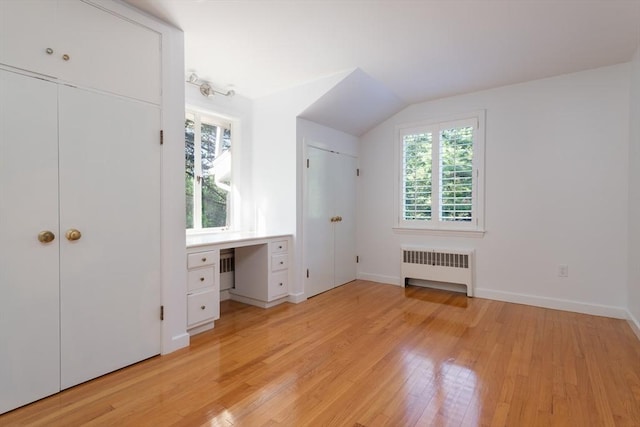 unfurnished bedroom featuring radiator, vaulted ceiling, and light hardwood / wood-style floors