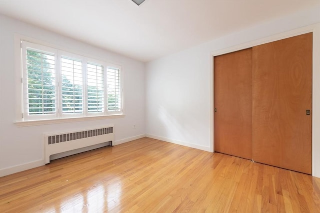 unfurnished bedroom with radiator, a closet, and light hardwood / wood-style floors