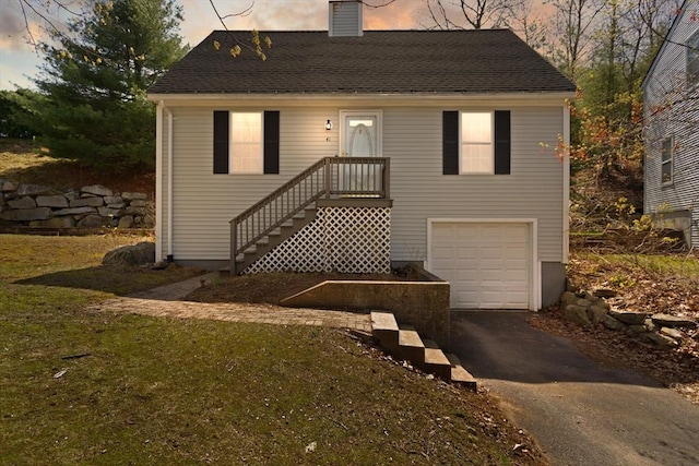 view of front of home featuring a garage, a chimney, and driveway