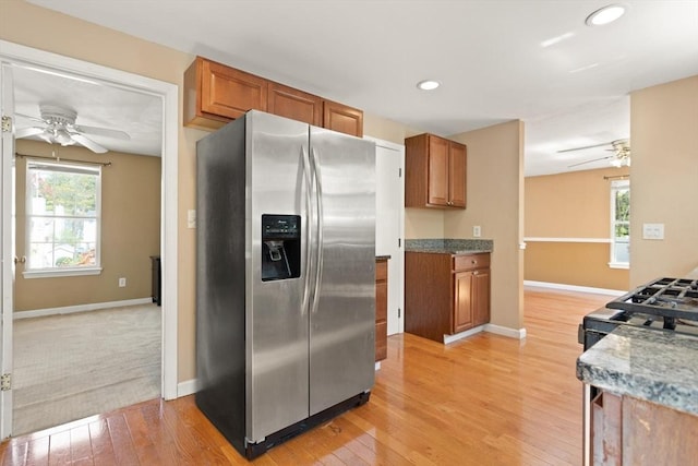 kitchen featuring brown cabinets, stainless steel refrigerator with ice dispenser, a ceiling fan, and baseboards