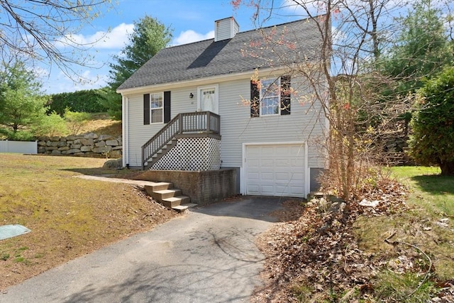 view of front of house featuring a garage, a shingled roof, a chimney, and driveway