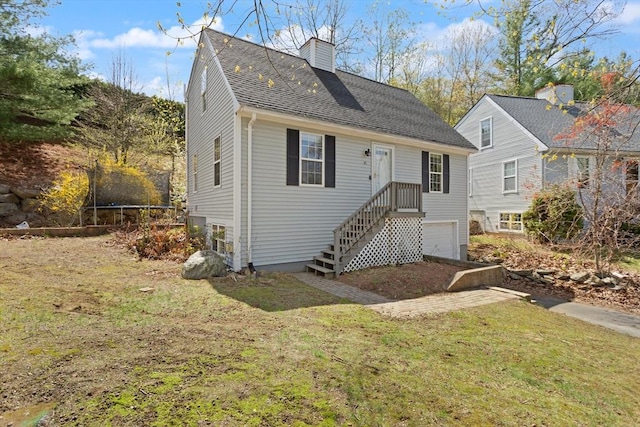 view of front of house featuring a chimney, a front yard, a trampoline, an attached garage, and a shingled roof