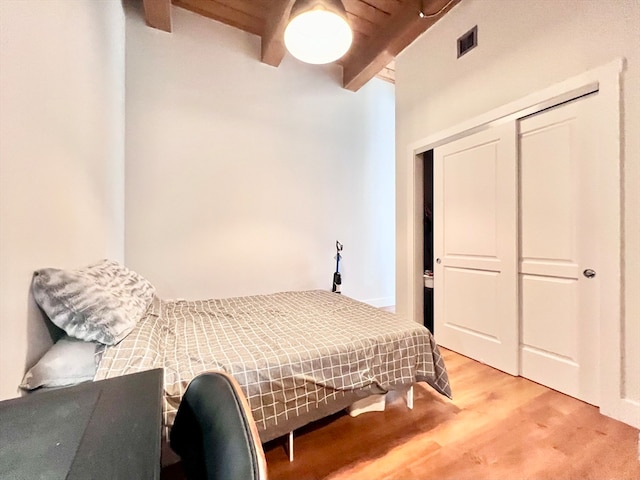 bedroom featuring beamed ceiling, ceiling fan, a closet, and light hardwood / wood-style floors