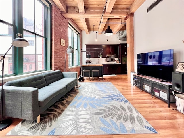 living room with wooden ceiling, light hardwood / wood-style floors, brick wall, and beamed ceiling