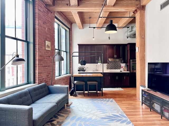 living room with wood ceiling, sink, beam ceiling, brick wall, and light hardwood / wood-style flooring