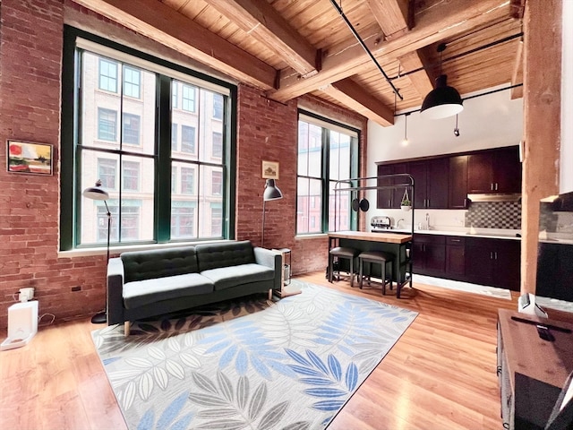 interior space with light wood-type flooring, wooden ceiling, beam ceiling, brick wall, and sink