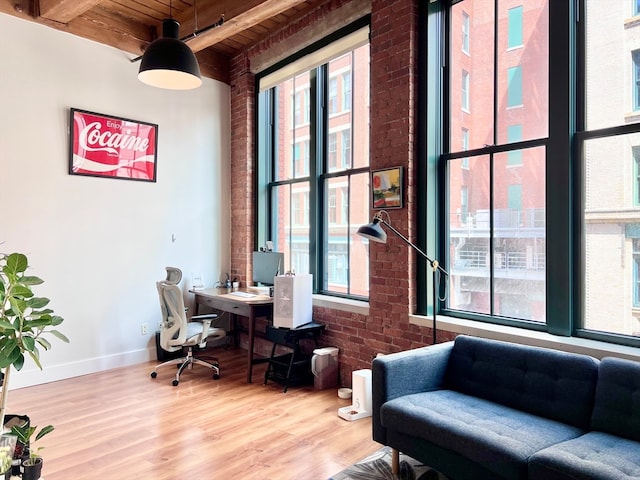 office space with wooden ceiling, beam ceiling, hardwood / wood-style floors, and brick wall