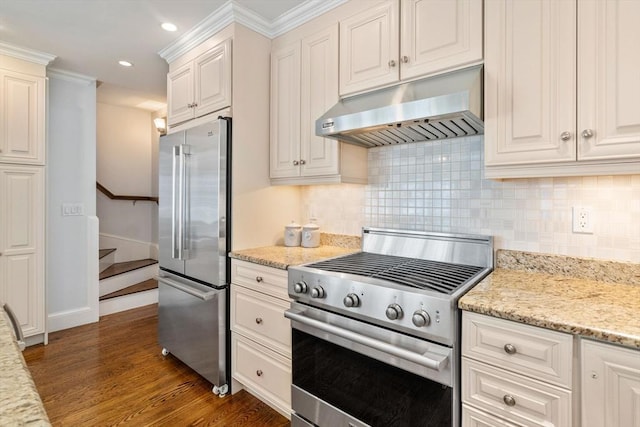 kitchen with dark wood-type flooring, crown molding, appliances with stainless steel finishes, light stone countertops, and exhaust hood