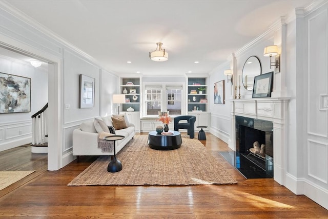 living room featuring crown molding, hardwood / wood-style floors, and built in features