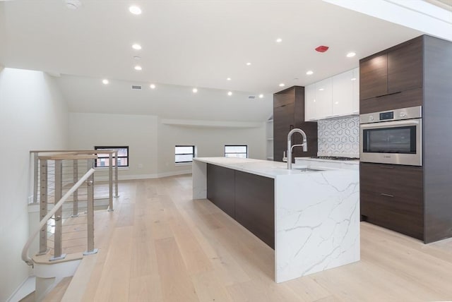 577 Massachusetts Ave Ph, Ph, Boston, MA 02118 - kitchen featuring modern cabinets, stainless steel oven, a sink, light wood finished floors, and a large island with sink