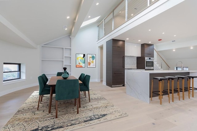 577 Massachusetts Ave Ph, Ph, Boston, MA 02118 - dining space with built in shelves, light wood finished floors, baseboards, lofted ceiling, and stairway