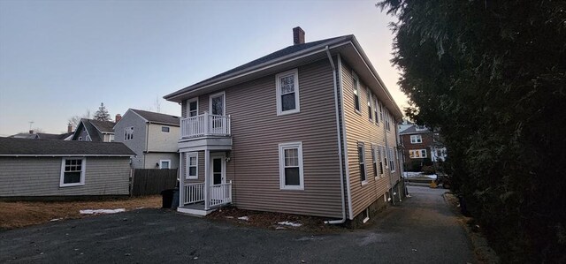 back of property featuring a balcony and a chimney