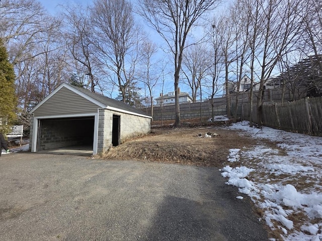 snow covered garage featuring a garage and fence