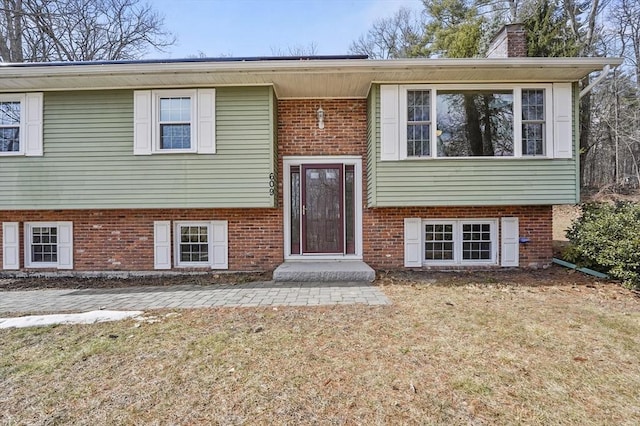 bi-level home with brick siding and a chimney