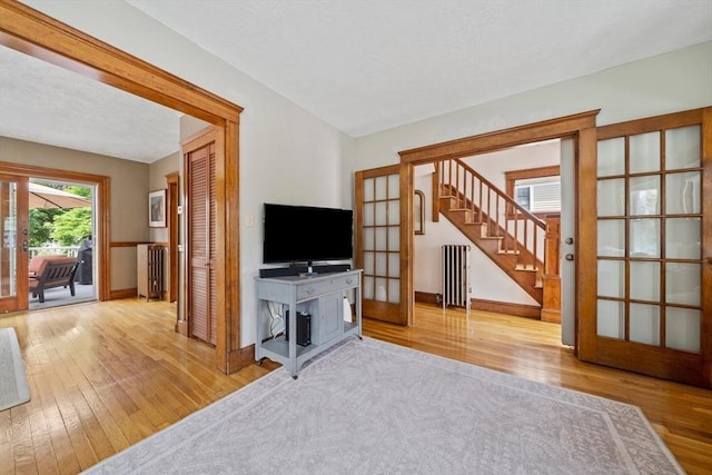 41 Dale Ave, Quincy, MA 02169 - living room featuring french doors, hardwood / wood-style flooring, stairway, radiator heating unit, and a textured ceiling