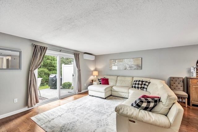 living room featuring a textured ceiling, hardwood / wood-style floors, and an AC wall unit