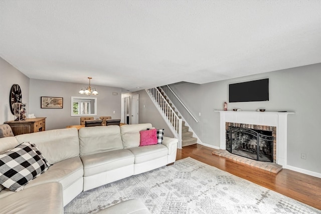 living room featuring a brick fireplace, hardwood / wood-style floors, and a chandelier