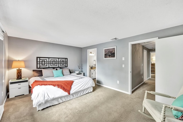 bedroom featuring ensuite bath, a textured ceiling, and light colored carpet