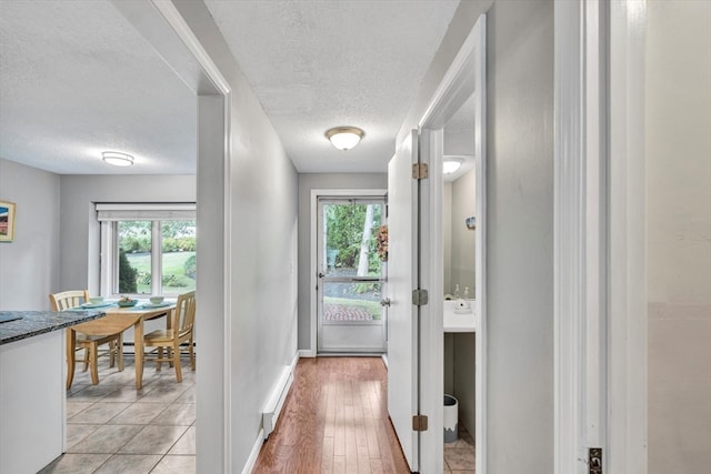 hallway with light wood-type flooring and a textured ceiling