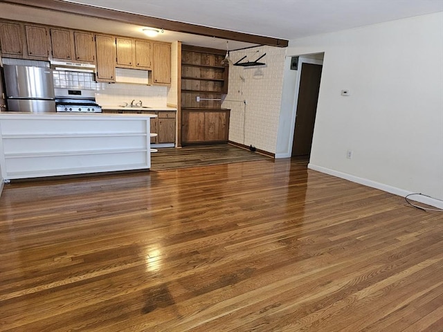 kitchen with baseboards, under cabinet range hood, a sink, dark wood finished floors, and stainless steel appliances