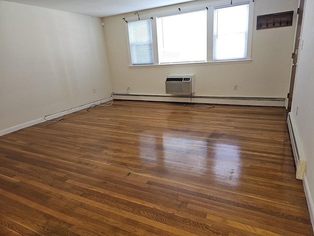 empty room featuring baseboard heating, plenty of natural light, wood finished floors, and a wall mounted air conditioner