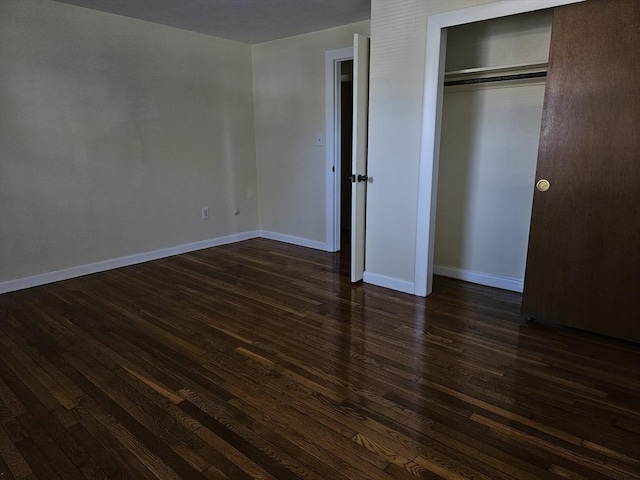 unfurnished bedroom with baseboards, dark wood finished floors, and a closet