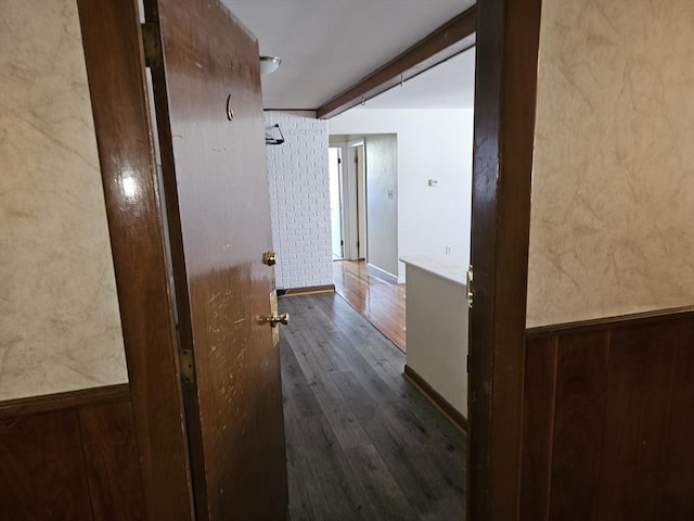 corridor featuring baseboards and dark wood-type flooring
