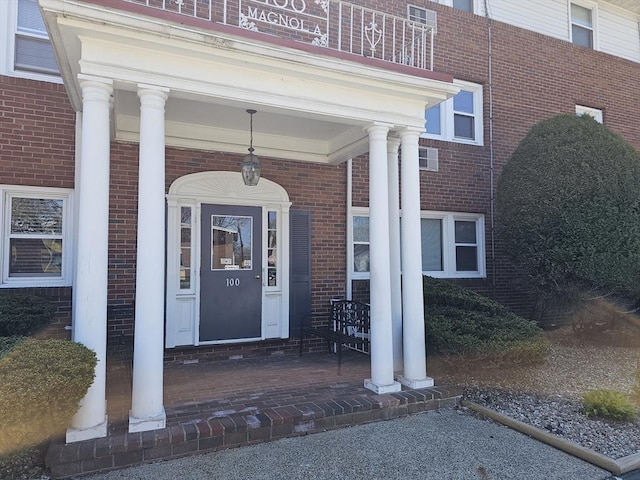 view of exterior entry with a porch and brick siding