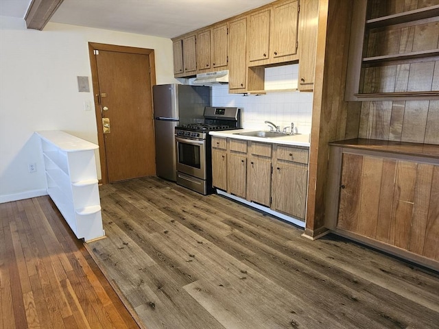 kitchen with open shelves, dark wood-type flooring, under cabinet range hood, a sink, and stainless steel appliances