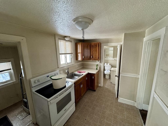 kitchen featuring white range with electric cooktop, washer / dryer, sink, and a textured ceiling