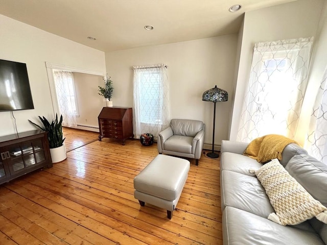 living room featuring baseboard heating, light wood-style floors, and recessed lighting