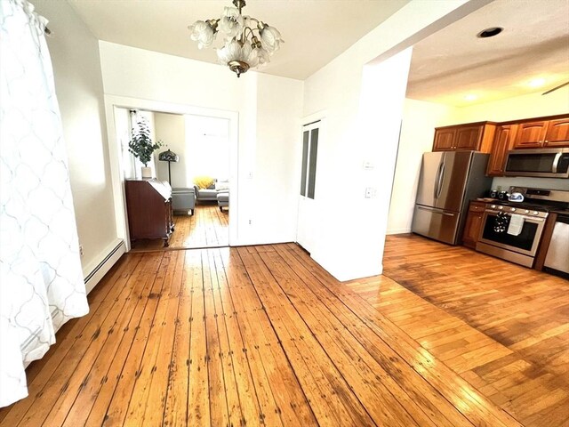 interior space featuring light wood-type flooring, baseboard heating, and a notable chandelier