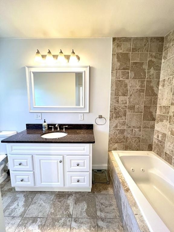 bathroom featuring baseboards, a tub with jets, and vanity