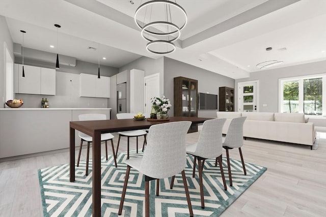 dining space with a tray ceiling, light wood-type flooring, and recessed lighting