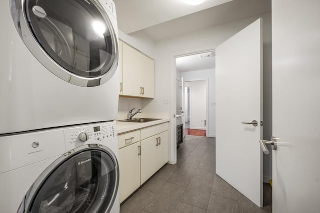 clothes washing area featuring cabinets, stacked washer / dryer, and sink