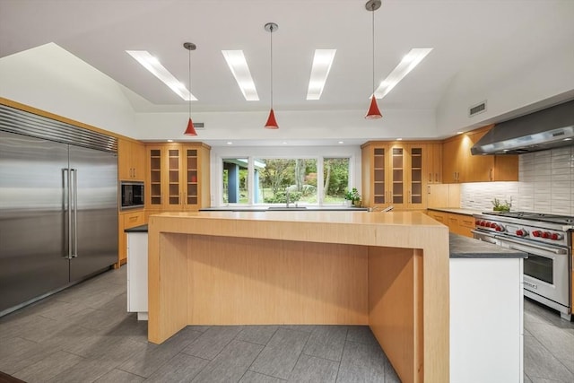 kitchen with decorative light fixtures, decorative backsplash, wall chimney exhaust hood, and built in appliances