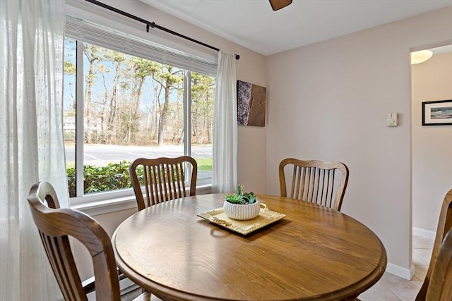 dining space with baseboards, a ceiling fan, and light tile patterned flooring