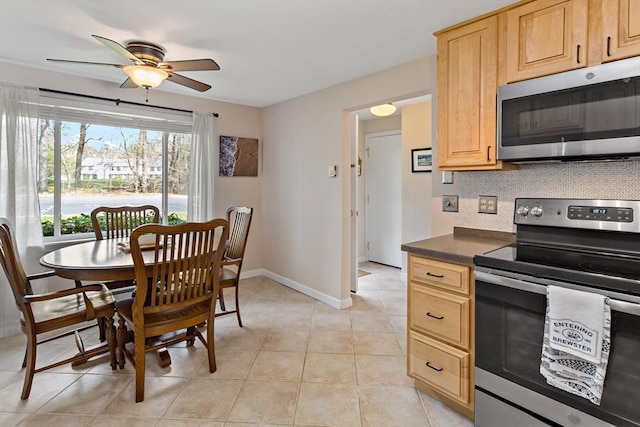 kitchen with light brown cabinetry, dark countertops, stainless steel appliances, a ceiling fan, and backsplash