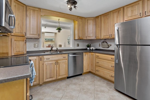 kitchen featuring dark countertops, appliances with stainless steel finishes, a sink, decorative backsplash, and light tile patterned floors