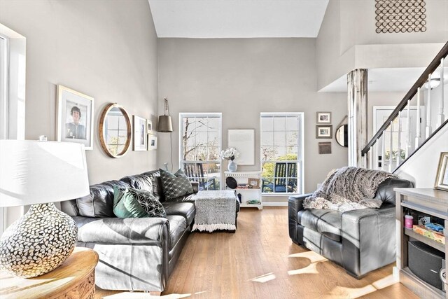 living area featuring stairs, a towering ceiling, and wood finished floors