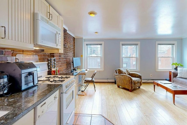 kitchen with light wood-type flooring, white appliances, dark stone counters, and plenty of natural light