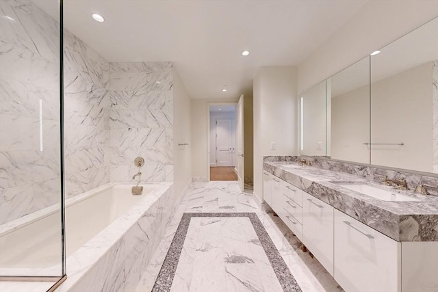 bathroom featuring tiled tub and vanity