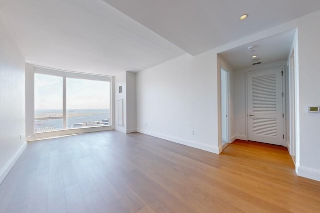 spare room featuring a water view and light wood-type flooring