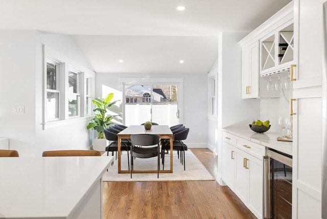 dining room featuring wine cooler, bar, and light hardwood / wood-style floors